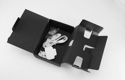 Black textured one-piece carton for handsets, size 3, opened out with a charger and cable inside